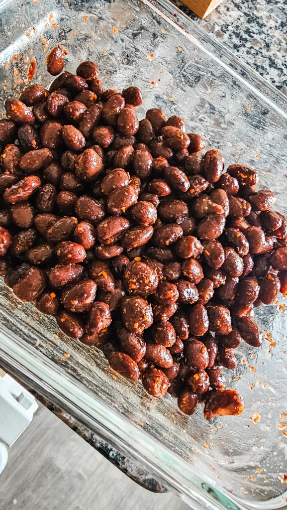 Meal prep protein hack: Black beans seasoned with Tajín chili lime powder in a clear glass storage container for quick addition to healthy recipes.