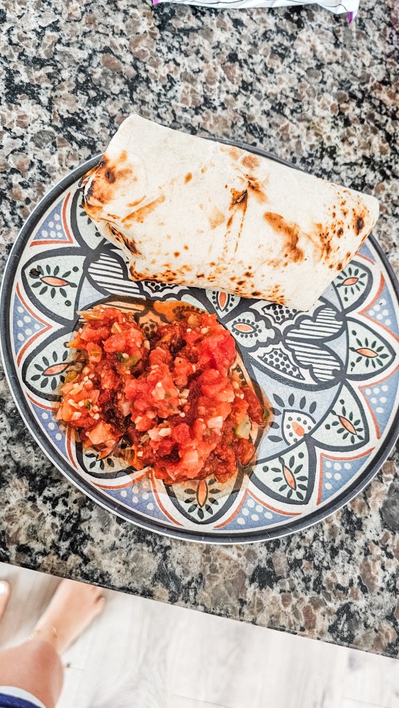 High protein breakfast burrito served with fresh salsa on a decorative plate