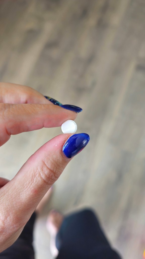 Sermorelin tablet held between fingers - oral peptide for sleep and growth hormone support from EllieMD