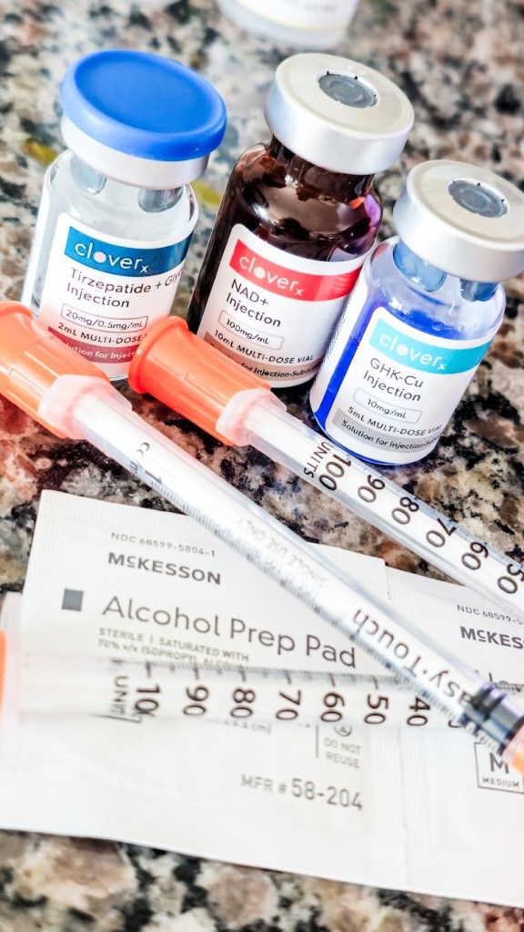 CloveRX tirzepatide with glycine, NAD+, and GHK-Cu injection vials prescribed through EllieMD telehealth, arranged with insulin syringes and McKesson alcohol prep pads on a granite countertop